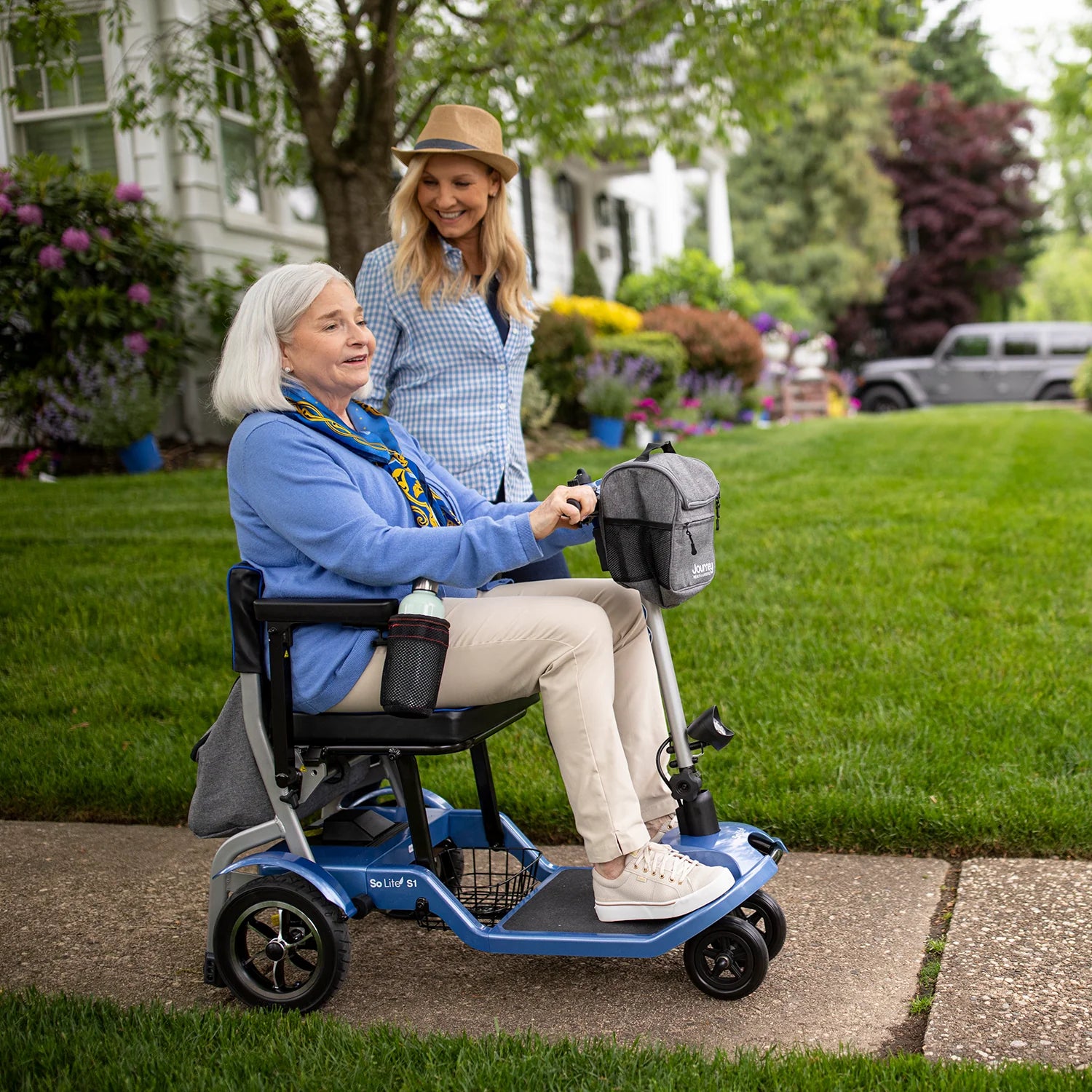Senior driving the Journey So Lite Lightweight Folding Power Scooter while talking to granddaughter